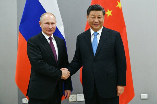 FILE - In this Nov. 12, 2019, file photo, Russian President Vladimir Putin, left, and China's President Xi Jinping shake hands prior to their talks on the sideline of the 11th edition of the BRICS Summit, in Brasilia, Brazil. China says Russian President Vladimir Putin's sudden announcement of constitutional changes that prompted the prime minister's departure won't affect increasingly close ties between Beijing and Moscow. (Ramil Sitdikov, Sputnik, Kremlin Pool Photo via AP)
