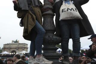 People wave French flags at the Louvre museum where Emmanuel Macron is planning to celebrate, Sunday, May 7, 2017 in Paris. Ripping up France's political map, French voters elected centrist Emmanuel Macron as the country's youngest president ever Sunday, delivering a resounding victory to the unabashedly pro-European former investment banker and strengthening France's place as a central pillar of the European Union. (AP Photo/Burhan Ozbilici)
