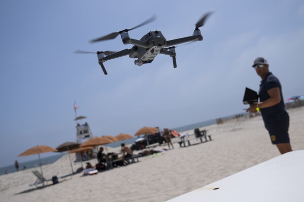 Cary Epstein, lifeguarding supervisor, operates a drone during takeoff for a shark patrol flight at Jones Beach State Park, Thursday, July 6, 2023, in Wantagh, N.Y. Drones are sweeping over the ocean off the coast of New York’s Long Island to patrol the waters for any danger possibly lurking. (AP Photo/John Minchillo)