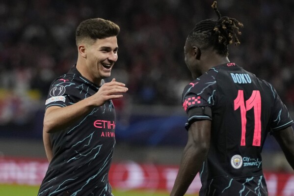 Manchester City's Julian Alvarez celebrates with his teammate Jeremy Doku after scoring his side's second goal during the Champions League group G soccer match between RB Leipzig and Manchester City in Leipzig, Germany, Wednesday, Oct. 4, 2023. (AP Photo/Matthias Schrader)