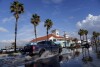 A car drives through a flooded parking lot in Huntington Beach, Calif., Thursday, Feb. 1, 2024. (AP Photo/Eric Thayer)