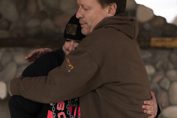 Jessica Pszonka hugs Dayn Brunner after they spoke during an interview while visiting the memorial for Oso landslide on Saturday, Feb. 17, 2024, in Oso, Wash. Dayn Brunner lost his sister Summer Raffo in the slide. Jessica Pszonka lost her sister Katie, two nephews, and three other family members. (AP Photo/Jenny Kane)