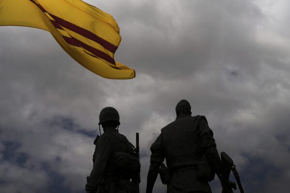 The flag of former South Vietnam flies above statues of two soldiers at the Vietnam War Memorial in the Little Saigon neighborhood of Westminster, Calif., Friday, April 25, 2025. (AP Photo/Jae C. Hong)
