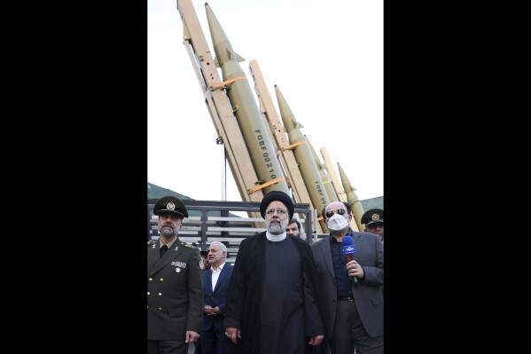 FILE - In this photo released by the Iranian Presidency Office, President Ebrahim Raisi, center, attends a ceremony to deliver the domestically built missiles to the armed forces as his Defense Minister Mohammad Reza Gharaei Ashtiani, left, Iran, on Aug. 22, 2023. Britain, France and Germany announced Thursday Sept. 14, 2023 they will keep their sanctions on Iran related to the Mideast country's atomic program and its development of ballistic missiles. (Iranian Presidency Office, via AP, File)