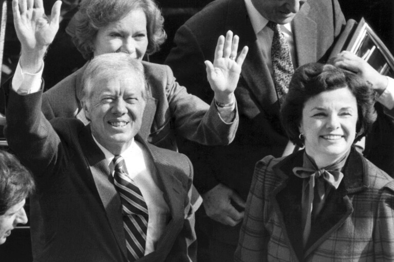 FILE - Former President Jimmy Carter and his wife, Rosalynn, back left, wave to photographers on the City Hall balcony as they arrived with San Francisco Mayor Dianne Feinstein, right, in San Francisco, Tuesday, Feb. 1, 1983. Carter's meeting with the mayor was canceled when a caller phoned in a routine bomb threat, the Secret Service said. (AP Photo/Eric Risberg, File)