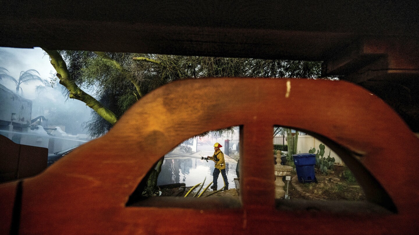 A firefighter hoses down the garage of Noel Piri's home that was destroyed by the Hawarden Fire in Riverside, Calif., on Sunday, July 21, 2024. (Terry Pierson/The Orange County Register via AP)
