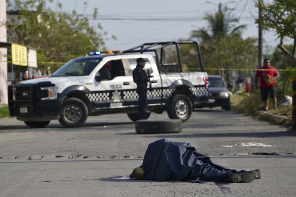 The body of a Veracruz state police officer lies in the middle of the road after he was fatally shot while patrolling in the Lomas de Rio Medio neighborhood of Veracruz, Mexico, March 12, 2024. (AP Photo/Felix Marquez)