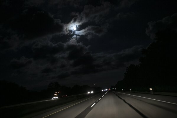 The moon shines through clouds along a highway in New Columbia, Ill., near Vienna, Ill., on Saturday, Aug. 1, 2020. "Sundown towns" like Vienna were places where Black people were allowed in during the day to work or shop but had to be gone by nightfall. Today, some still exist in various forms, enforced now by tradition and fear rather than by rules. (AP Photo/Wong Maye-E)