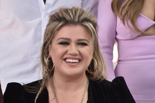 Singer and talk show host Kelly Clarkson poses with a replica of her new star on the Hollywood Walk of Fame during a ceremony in her honor on Monday, Sept. 19, 2022, in Los Angeles. A clip and comments from Clarkson's Instagram page have been edited to add fake promotions for weight-loss gummies. (Photo by Jordan Strauss/Invision/AP)