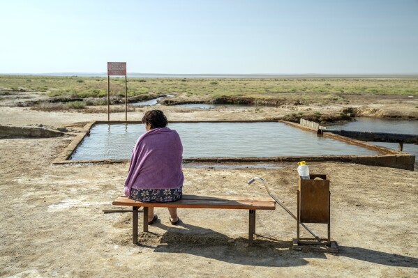 A woman relaxes next to a hot spring, in an area that used to be part of the Aral Sea, near Aralsk, Kazakhstan, Tuesday, July 3, 2023. (AP Photo/Ebrahim Noroozi)