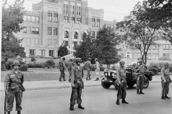 A command jeep patrols the area in front of Central High School in Little Rock, Ark., Sept. 25, 1957, as troops of the 101st Airborne Division stand with fixed bayonets.  The troops were sent to keep order in the integration of the school.  (AP Photo)