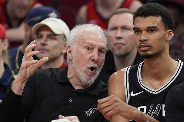 San Antonio Spurs coach Gregg Popovich, left, talks with Victor Wembanyama on the bench during the first half of an NBA basketball game against the Houston Rockets Tuesday, March 5, 2024, in Houston. (AP Photo/David J. Phillip)