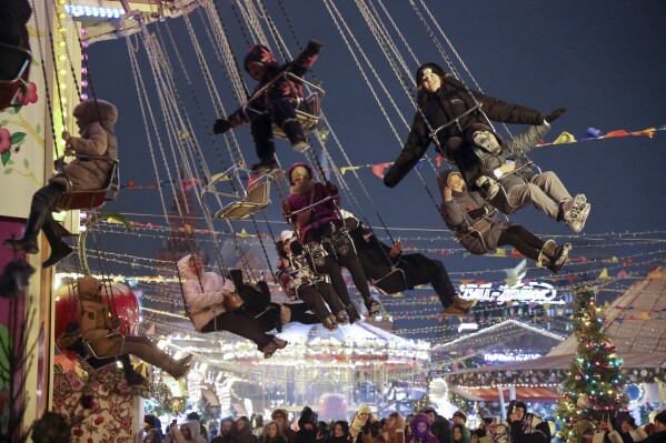Children and their parents ride a carousel at a Christmas Market set up in Red Square decorated for the New Year and Christmas festivities in Moscow, Russia, Sunday, Dec. 31, 2023. The Red Square will be closed for celebrations on the New Year's Eve. (AP Photo/Marina Lystseva)