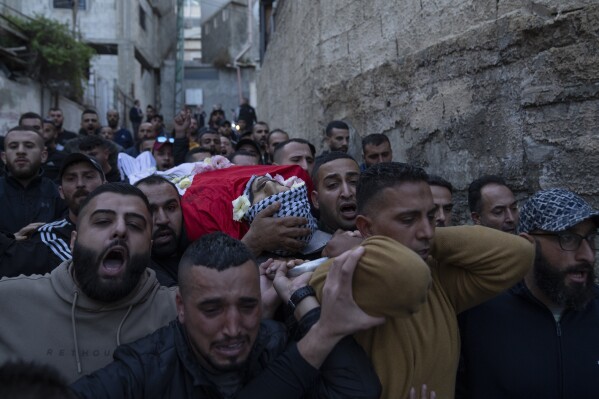 Palestinian mourners carry the body of Ali Alqam, 32, during his funeral in the West Bank refugee camp of Qalandia, south of Ramallah, Monday, Dec. 4, 2023. The Palestinian health ministry said the Alqam was killed during an Israeli army raid in Qalandia this morning. (AP Photo/Nasser Nasser)