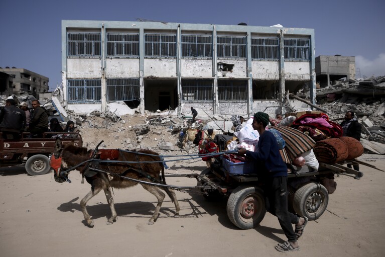 Palestinians carry their belongings after visiting their houses destroyed in the Israeli offensive on Khan Younis, Gaza Strip, Wednesday, March 6, 2024. (AP Photo/Mohammed Dahman)