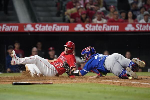 Los Angeles Angels' Mike Trout (27) is tagged out at home by Toronto Blue Jays catcher Alejandro Kirk (30) during the fifth inning of a baseball game in Anaheim, Calif., Friday, May 27, 2022. (AP Photo/Ashley Landis)