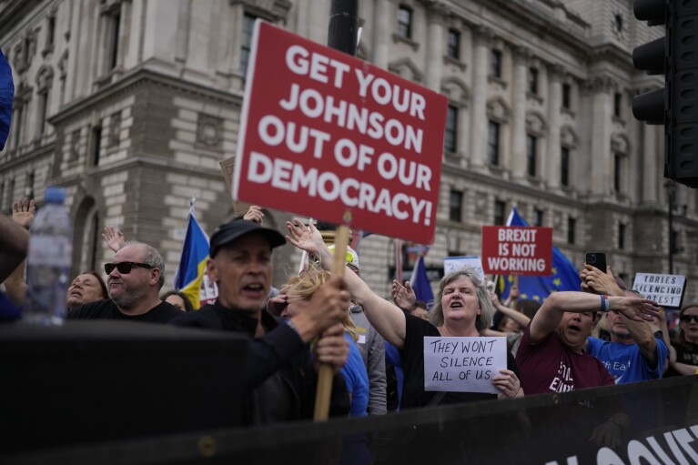 Anti-Brexit protesters sing to music standing on a traffic island across the street from the Houses of Parliament, in London, Wednesday, June 29, 2022. (AP Photo/Matt Dunham, File)