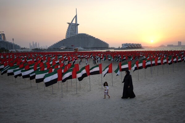 FILE - An Emirati mother walks with her daughter in front of six thousands flags are on display to celebrate the country's Flag Day in Dubai, United Arab Emirates, Nov. 4, 2023. Dubai hosts the United Nations COP28 climate talks starting Nov. 30. (AP Photo/Kamran Jebreili, File)