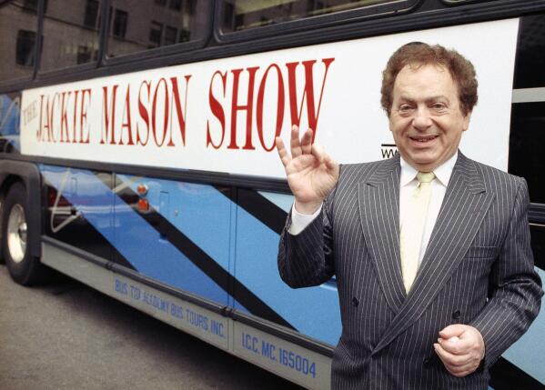 FILE - Actor/comedian Jackie Mason stands beside a bus displaying a sign advertising his TV show, 1992. Mason, a rabbi-turned-jokester whose feisty brand of standup comedy got laughs from nightclubs in the Catskills to West Coast talk shows and Broadway stages, has died. He was 93. Mason died Saturday, July 24, 2021, in Manhattan, the celebrity lawyer Raoul Felder told The Associated Press. (AP Photo/File)
