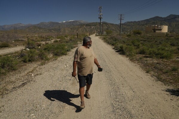 Glenn Chavez sets the distance for which a helicopter pilot can remotely turn on a Heli-Hydrant, a small, open tank that helicopters can rely on to get water faster for urban fires, Friday, April 11, 2025, in Cabazon, Calif. (AP Photo/Brittany Peterson)
