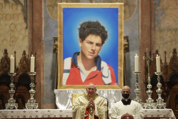 FILE - An image of 15-year-old Carlo Acutis, an Italian boy who died in 2006 of leukemia, is seen during his beatification ceremony celebrated by Cardinal Agostino Vallini, center, in the St. Francis Basilica, in Assisi, Italy, on Oct. 10, 2020. Pope Francis has paved the way for the canonization of the first saint of the millennial generation on Thursday, attributing a second miracle to a 15-year-old Italian computer whiz who died of leukemia in 2006. Carlo Acutis, born on May 3, 1991, in London and then moved with his Italian parents to Milan as a child, was the youngest contemporary person to be beatified by Francis in Assisi in 2020. (AP Photo/Gregorio Borgia, File)
