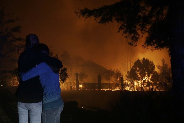 Two women hug as they watch houses burn in Santa Rosa, Calif., Monday, Oct. 9, 2017. (AP Photo/Jeff Chiu)