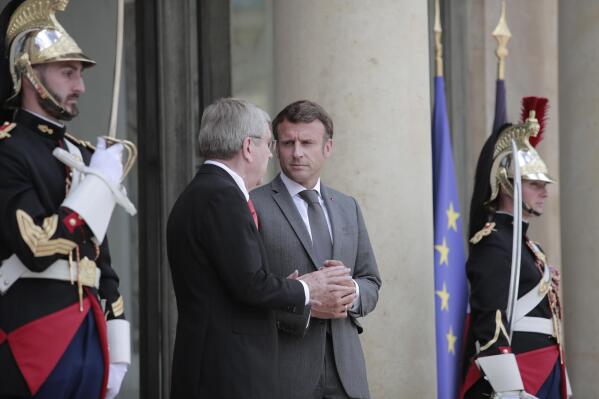 International Olympic Committee's President Thomas Bach, left, talks to French President Emmanuel Macron as he leaves the Elysee Palace in Paris, Monday, July 25, 2022. Tomorrow is marking two years until the Olympics are due to begin in the French capital. (AP Photo/Lewis Joly, Pool)