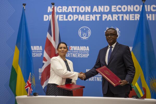 Britain's Home Secretary Priti Patel, left, shakes hands with Rwanda's Minister of Foreign Affairs Vincent Biruta, right, after signing what the two countries called an "economic development partnership" in Kigali, Rwanda Thursday, April 14, 2022. Britain's Conservative government has struck a deal to send some asylum-seekers thousands of miles away to Rwanda, a move that British opposition politicians and refugee groups condemned as inhumane, unworkable and a waste of public money. (AP Photo/Muhizi Olivier)
