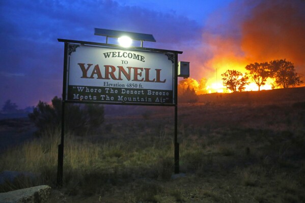 FILE - A wildfire burns homes in Yarnell, Ariz., June 30, 2013. Friday, June 30, 2023, marks 10 years since one of the deadliest wildland fires in the U.S. killed 19 members of an elite central Arizona crew. The city of Prescott, Ariz., and neighboring town of Yarnell are honoring the Granite Mountain Hotshots with public events, including 19 bell tolls. (David Kadlubowski/The Arizona Republic via AP, File)
