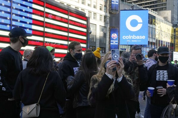 Coinbase employees gather outside the Nasdaq MarketSite during the company's IPO, in New York's Times Square, Wednesday, April 14, 2021. Wall Street will be focused on Coinbase Wednesday with the digital currency exchange becoming a publicly traded company. (AP Photo/Richard Drew)