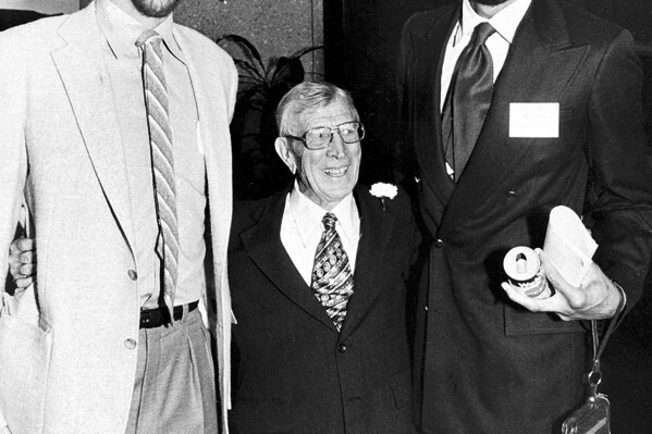 FILE - Former UCLA NCAA college basketball coach John Wooden, center, is flanked by UCLA alumni stars Bill Walton, left, and Kareem Abdul-Jabbar during a birthday party for Wooden in Los Angeles, Oct. 20, 1980. (AP Photo/File)