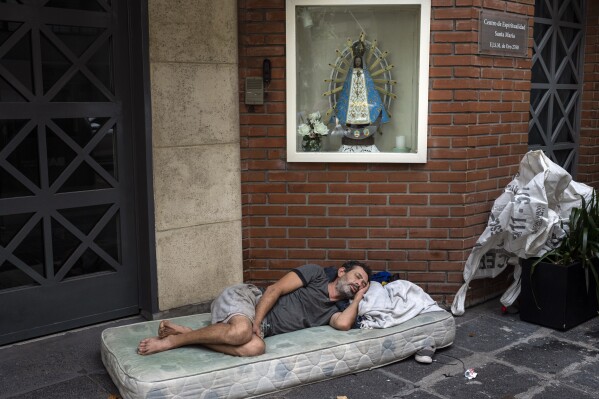 Agustin Catamano, 48, who said he is homeless, sleeps in front of a Catholic institution in Buenos Aires, Argentina, Sunday, Feb. 18, 2024. (AP Photo/Rodrigo Abd)