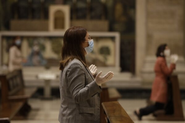 Faithful wearing gloves and face masks to prevent the spread of COVID-19, pray during the morning mass at St. Eugenio Church, in Rome, Monday, May 18, 2020. Italy partially lifted sanitary restrictions Monday after a two-month coronavirus lockdown. (AP Photo/Alessandra Tarantino)