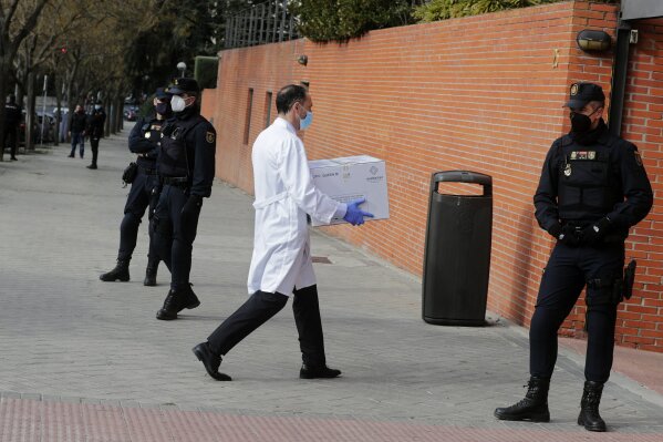 FILE - In this Sunday, Dec. 27, 2020 file photo, Police stand by the entrance of a nursing home as a box of some of the first Pfizer coronavirus vaccines arrives in Madrid, Spain. Spain plans to receive over 4.5 million doses of the vaccine over the next three months, enough it says to immunize just over 2.2 million people. The government estimates that this first phase will be enough to cover nursing home residents and workers, followed by health workers in general and people with disabilities. (AP Photo/Paul White, File)