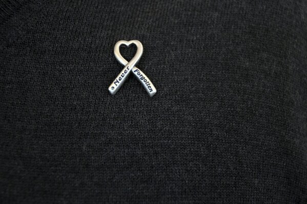 
              In this Saturday, March 23, 2019 photo, a pin on Rick Townsend's sweater memorializes his daughter, Lauren, who was killed in the April 20, 1999, mass shooting at Columbine High School in suburban Denver. Several survivors and family members of the victims gathered at the school's library to speak to the media Saturday. (AP Photo/Thomas Peipert)
            