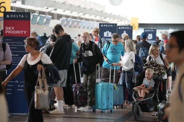 Travelers queue up at the Delta Airlines ticket counter at Denver International Airport Thursday, July 13, 2023, in Denver. (AP Photo/David Zalubowski)