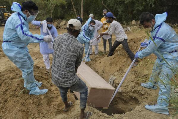 Relatives bury the body of a COVID-19 victim at a graveyard in New Delhi, India, Tuesday, May 4, 2021. India's official count of coronavirus cases surpassed 20 million Tuesday, nearly doubling in the past three months, while deaths officially have passed 220,000. Staggering as those numbers are, the true figures are believed to be far higher, the undercount an apparent reflection of the troubles in the health care system. (AP Photo/Ishant Chauhan)