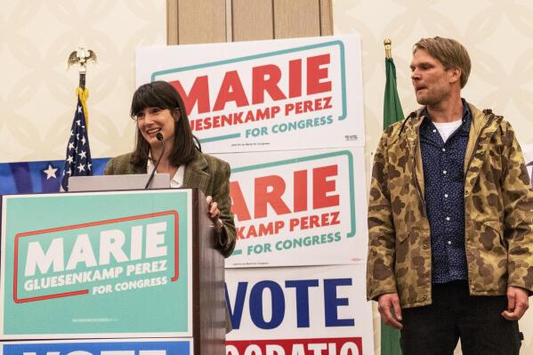 Marie Gluesenkamp Perez, left, speaks to a crowd of supporters while her husband Dean Gluesenkamp looks at during the Clark County Democrats election night watch party at a hotel in Vancouver, Wash., Tuesday, Nov. 8, 2022. (Taylor Balkom/The Columbian via AP)