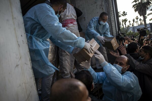 Palestinian workers unload a truck from 20,000 doses of Russian-made Sputnik V vaccine upon its arrival to Gaza Strip, at the Rafah crossing border with Egypt, Sunday, Feb. 21, 2021. The 20,000 doses of Russia's Sputnik V, donated by the United Arab Emirates and organized by Abbas rival Mohammed Dahlan, entered the Palestinian enclave through its border with Egypt. (AP Photo/Khalil Hamra)