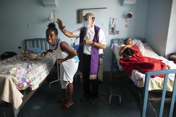 Father Felix Mendoza, a Venezuelan Catholic priest, center, prays over a woman who cries, saying she is in physical pain, at a public hospital in Caracas, Venezuela, Tuesday, May 11, 2021, amid the new coronavirus pandemic. Father Felix has been visiting patients at the hospital to comfort the sick, for the last 20 years. (AP Photo/Ariana Cubillos)