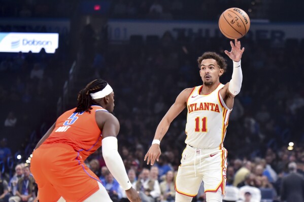 Atlanta Hawks guard Trae Young (11) passes the ball over Oklahoma City Thunder guard Luguentz Dort (5) in the first half of an NBA basketball game, Monday, Nov. 6, 2023, in Oklahoma City. (AP Photo/Kyle Phillips)