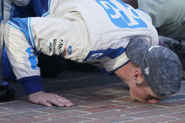Austin Cindric kisses the yard of bricks after winning the NASCAR Xfinity Series auto race at Indianapolis Motor Speedway, Saturday, Aug. 14, 2021, in Indianapolis. (AP Photo/Darron Cummings)