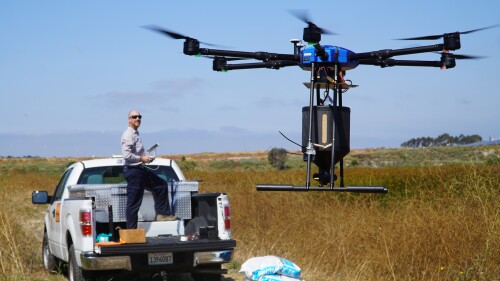 Drone pilot John Savage flies the hexacopter drone loaded with anti-mosquito bacterial spore pellets at the San Joaquin Marsh Reserve at University of California in Irvine, Calif., on June 27, 2023. The drone is the latest technology deployed by the Orange County Mosquito and Vector Control District to attack mosquitoes developing in marshes, wetlands, large ponds and parks. (AP Photo/Eugene Garcia)