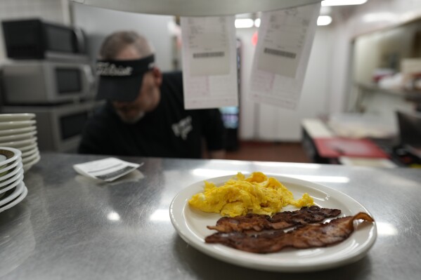 Bacon and eggs are up to serve as Chris Barton cooks at the grill at the Pepper Pod Restaurant, Thursday, Feb.13, 2025, Newport, Ky. (AP Photo/Carolyn Kaster)