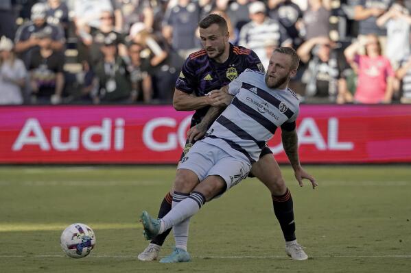 Sporting Kansas City forward Johnny Russell (7) kicks the ball under pressure from Seattle Sounders forward Jordan Morris during the second half of an MLS soccer match Sunday, Oct. 2, 2022, in Kansas City, Kan. (AP Photo/Charlie Riedel)
