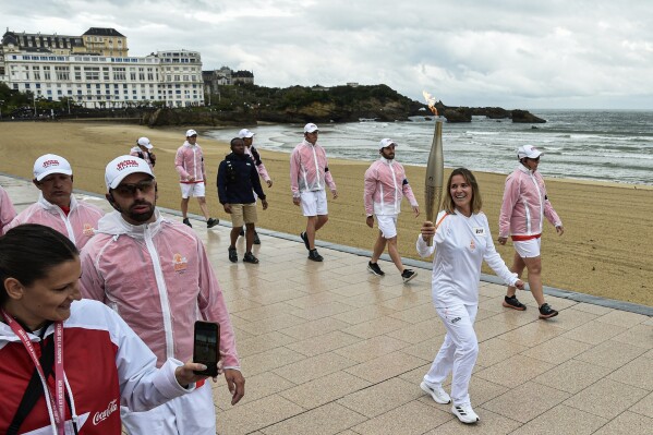 FILE - Zoe Grospiron carries the Olympic torch in Biarritz, southwestern France, Monday May 20, 2024. A man in France who posted online about a deadly rampage in California in 2014 has been taken in custody and has told police investigators he'd been thinking about an attack of his own, the French prosecutor overseeing the police probe in Bordeaux said Thursday May 23, 2024. A French media report says that the 26-year-old man was suspected of planning "a mass killing" Thursday, when the Olympic flame was passing through Bordeaux-region wine country to finish in the city itself (AP Photo/Nicolas Mollo, File)
