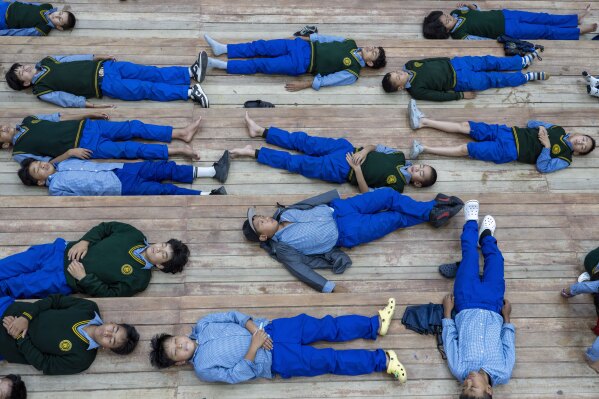 Exiled Tibetan children lie on the floor as they mark International Day of Yoga at the Tibetan Children's Village School in Dharamshala, India, Saturday, June 21, 2025. (AP Photo/Ashwini Bhatia)