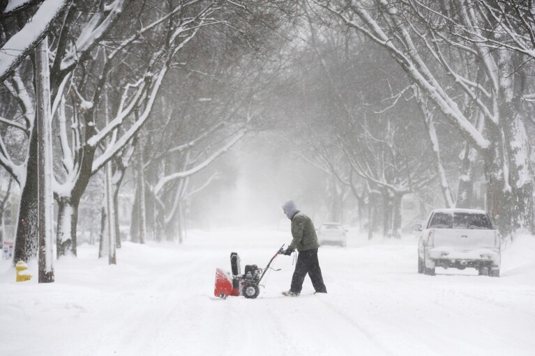 Un hombre se prepara para quitar la nieve a lo largo de una acera en State Street en St. Joseph, Michigan, el lunes 15 de enero de 2024. Don Campbell/The Herald-Palladium vía AP)