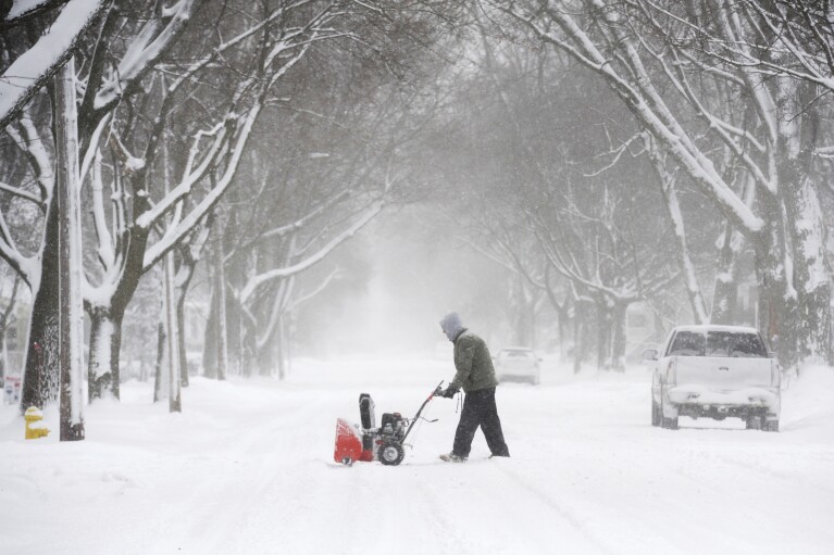 A man prepares to clear snow along a sidewalk on State Street in St. Joseph, Mich., Monday, Jan. 15, 2024. Don Campbell/The Herald-Palladium via AP)