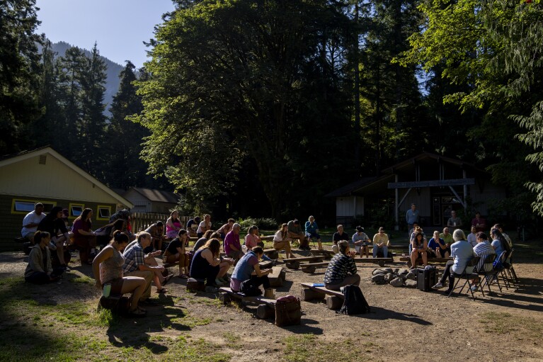 Attendees gather for a morning session on the log benches at NatureBridge in the Olympic National Park during the 2023 Tribal Climate Camp, Thursday, Aug. 17, 2023, near Port Angeles, Wash. (AP Photo/Lindsey Wasson)